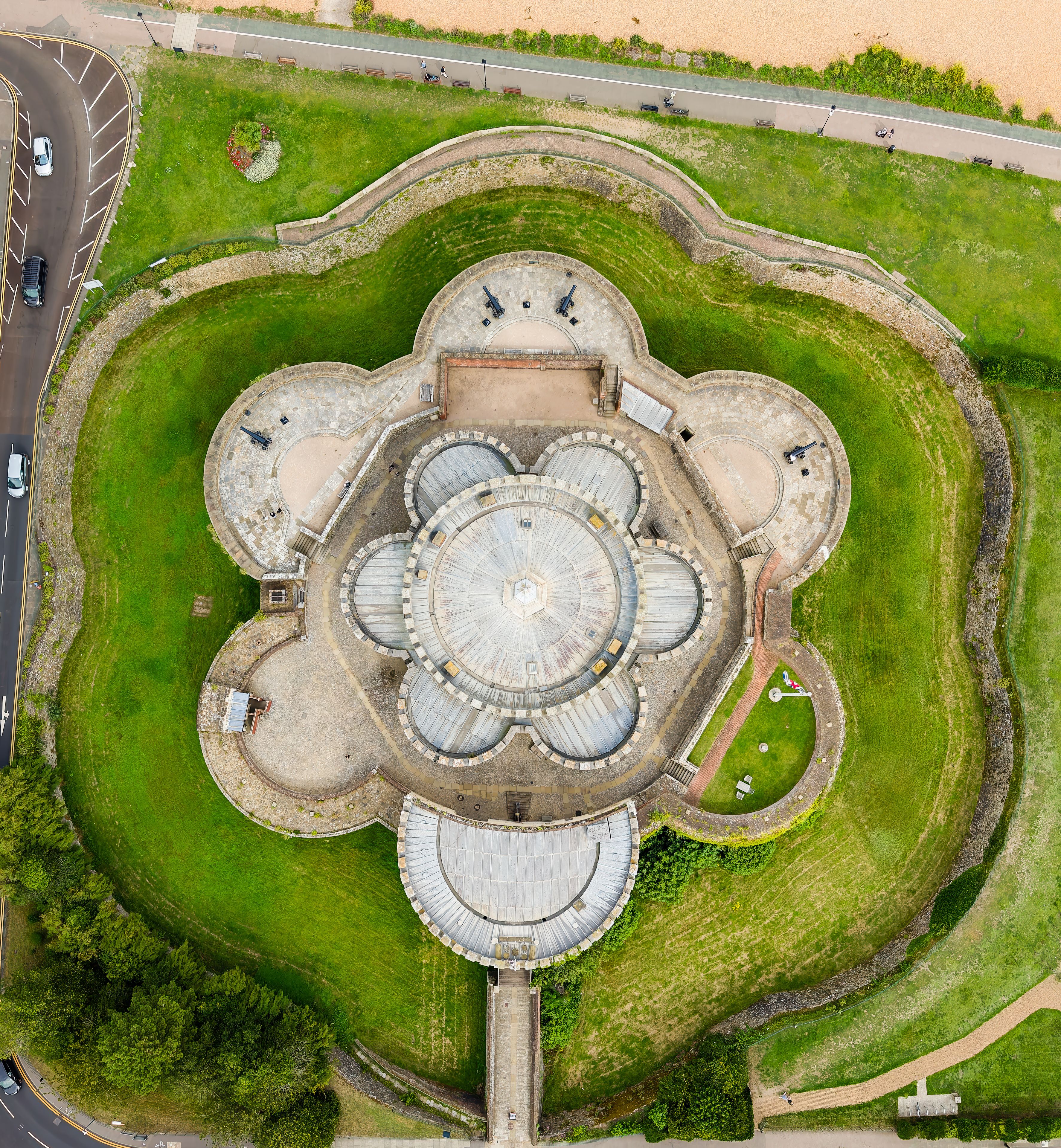 An aerial view of a circular architectural complex with multiple domes and a surrounding green park.