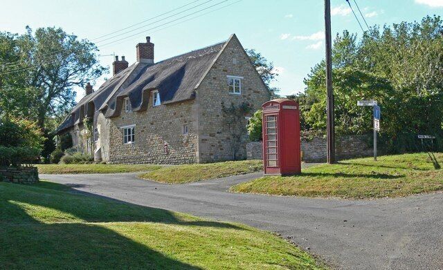 A stone house with a red telephone booth and a street sign.