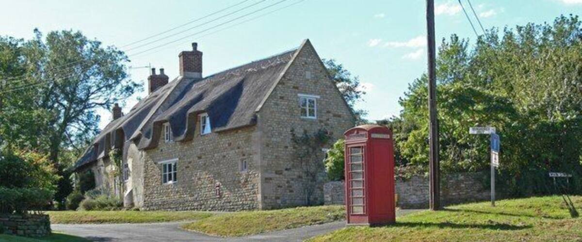 A stone house with a red telephone booth and a street sign.