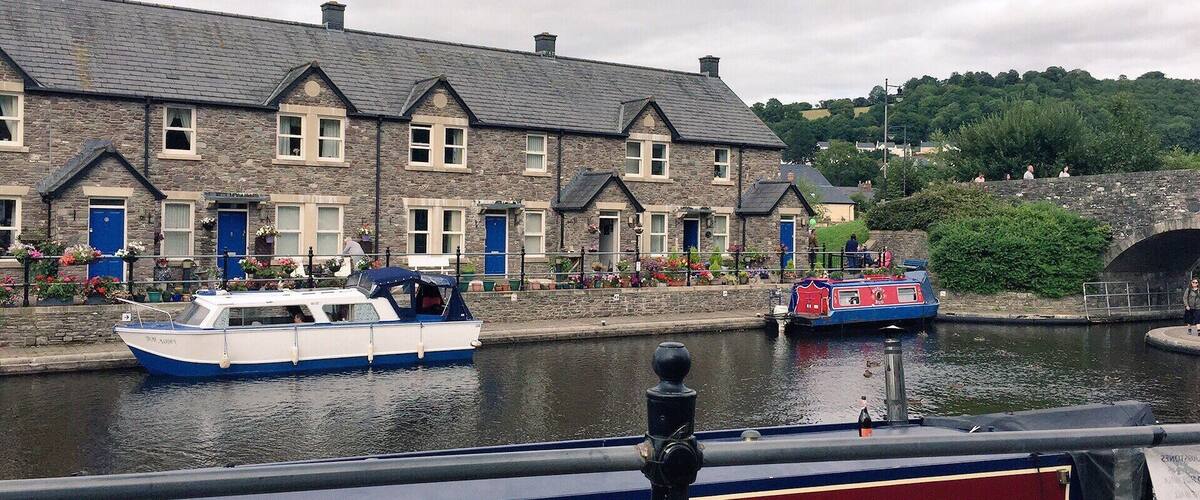 A canal with boats, stone buildings, and a bridge.