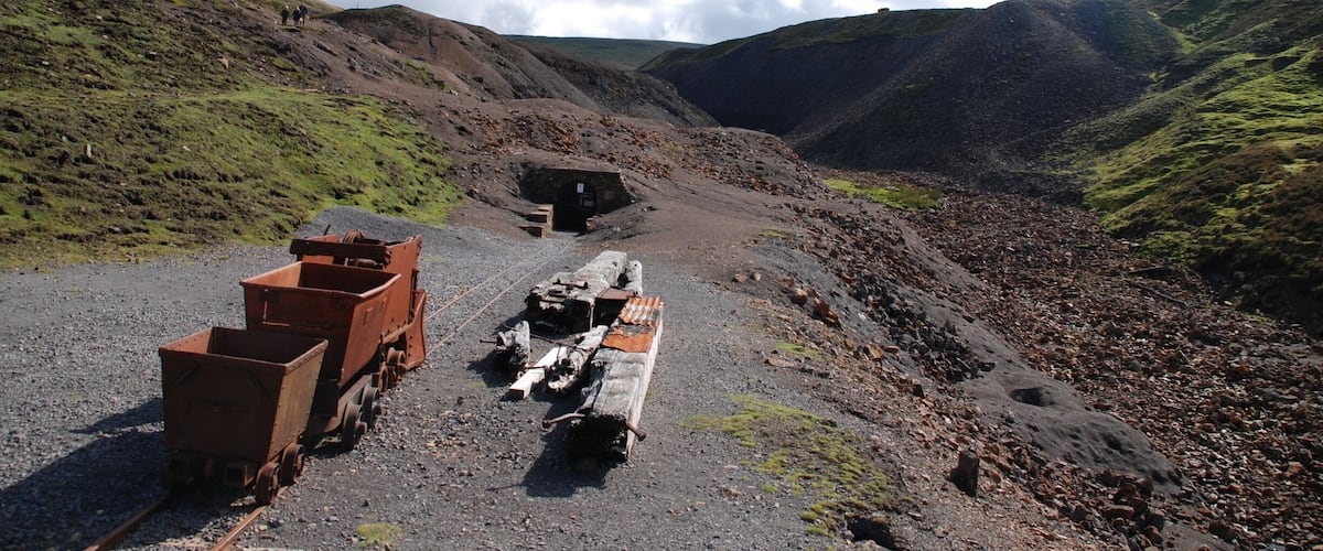 A railway track with a train car and a caboose in a mountainous area.