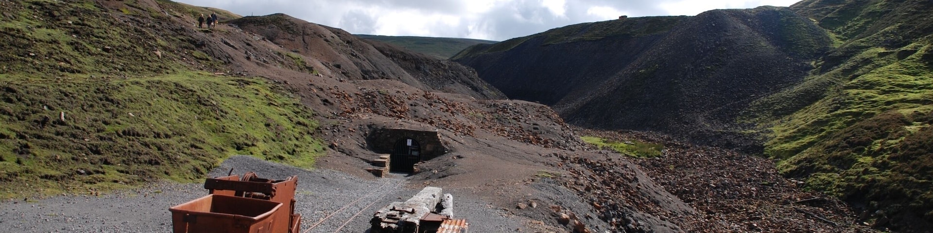 A railway track with a train car and a caboose in a mountainous area.