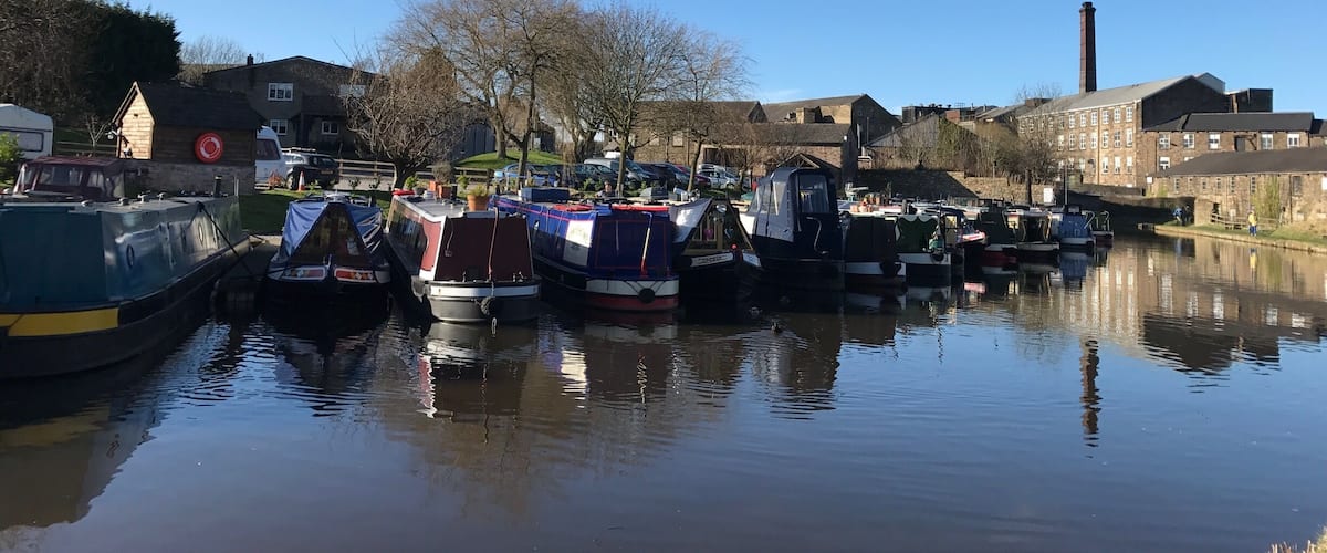 A calm river with several boats docked along the banks.