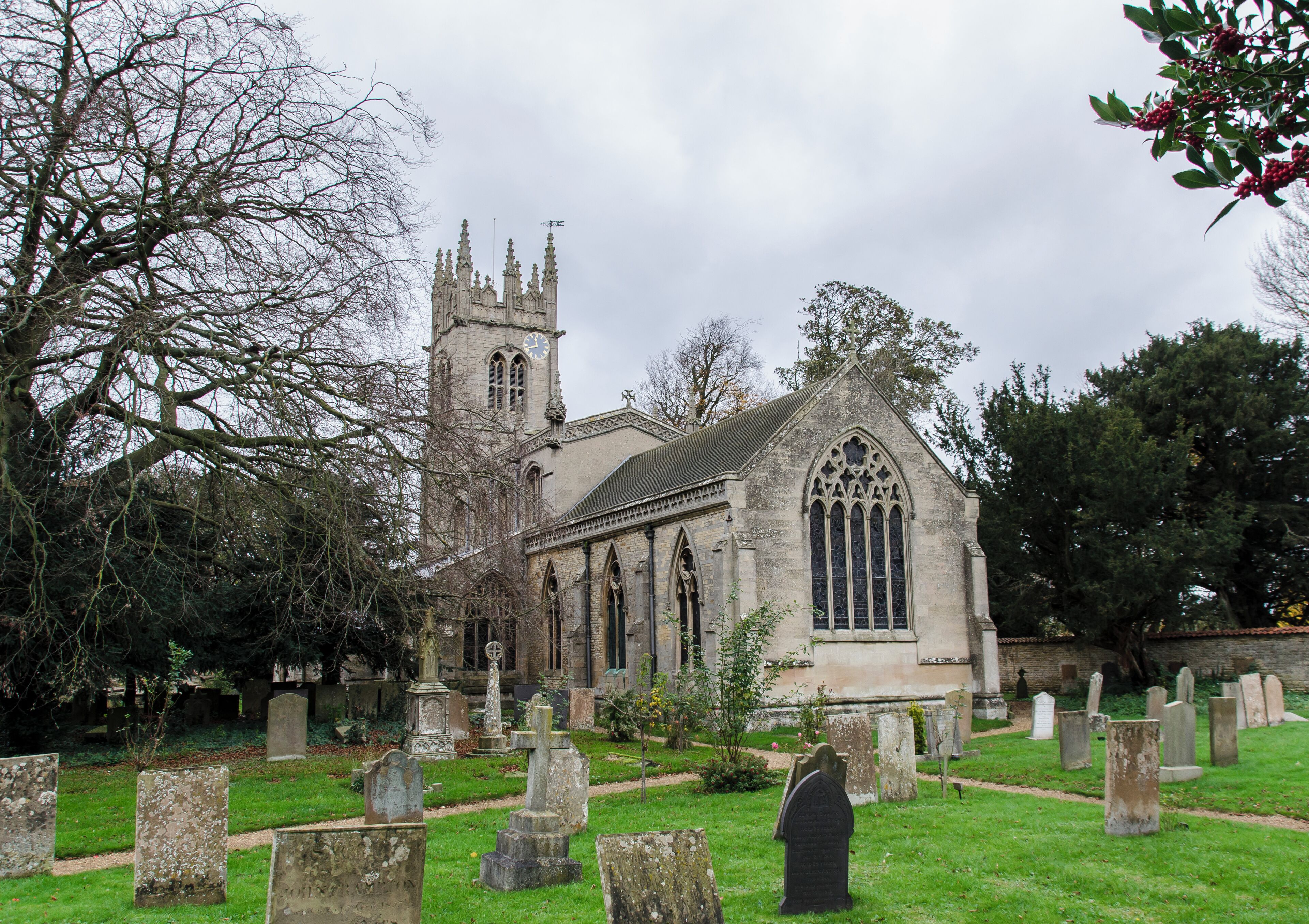 A historic church with a tall tower and Gothic architecture, surrounded by a cemetery with headstones.