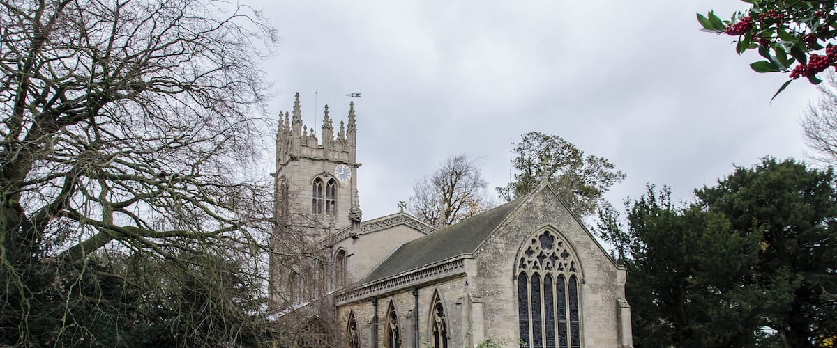 A historic church with a tall tower and Gothic architecture, surrounded by a cemetery with headstones.