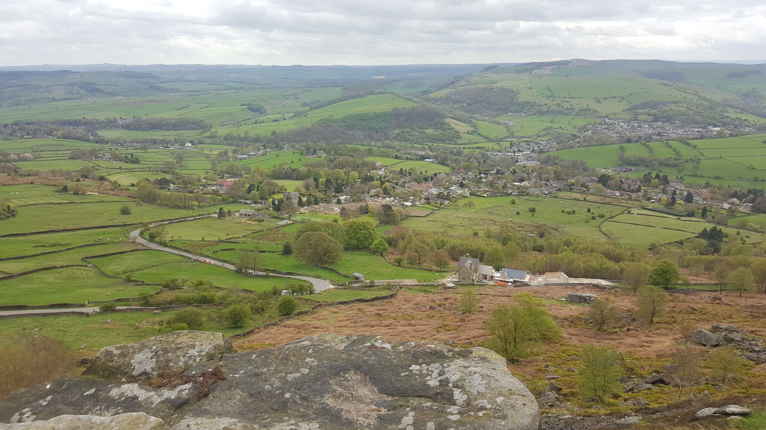 A rural landscape with rolling hills, fields, and a small village.