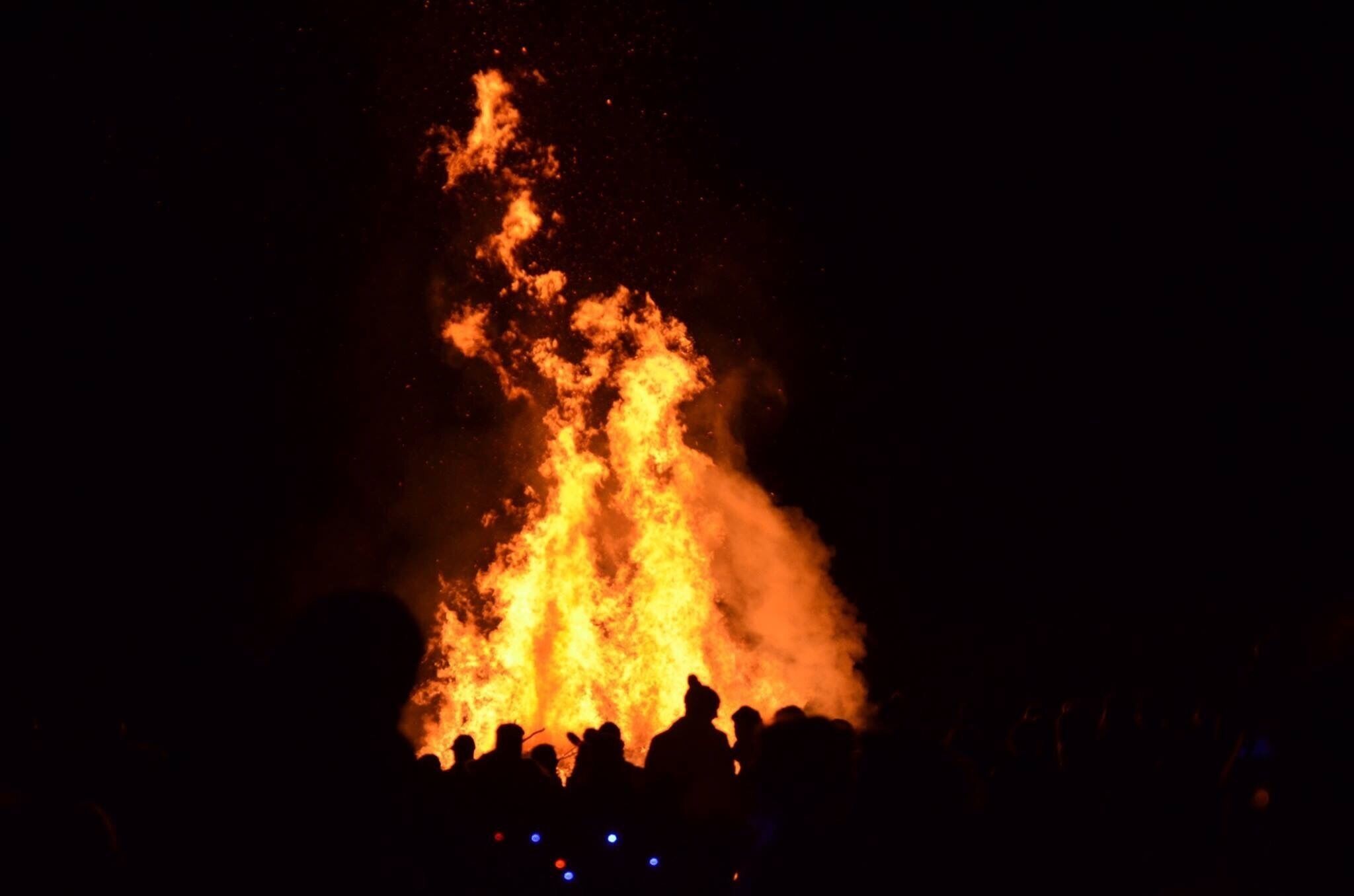A large fire with smoke rising into the night sky.
