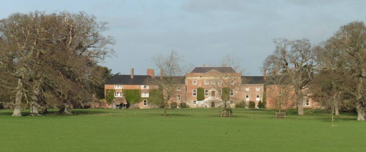 A large green field with a brick building in the background.