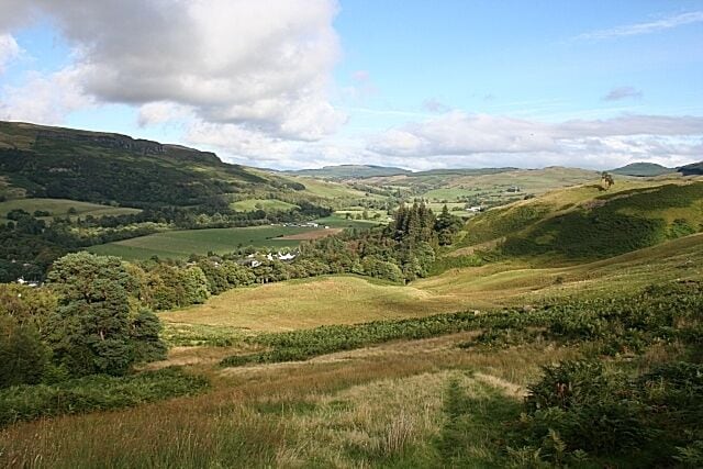 Endrick Water A slight misnomer, as the river itself is obscured by vegetation. Its course is among the trees at the left of the flat fields in the floor of the glen. The Fintry Hills are on the left, and part of the village of Fintry is at the foot of the foreground slope, beyond Fintry Wood.