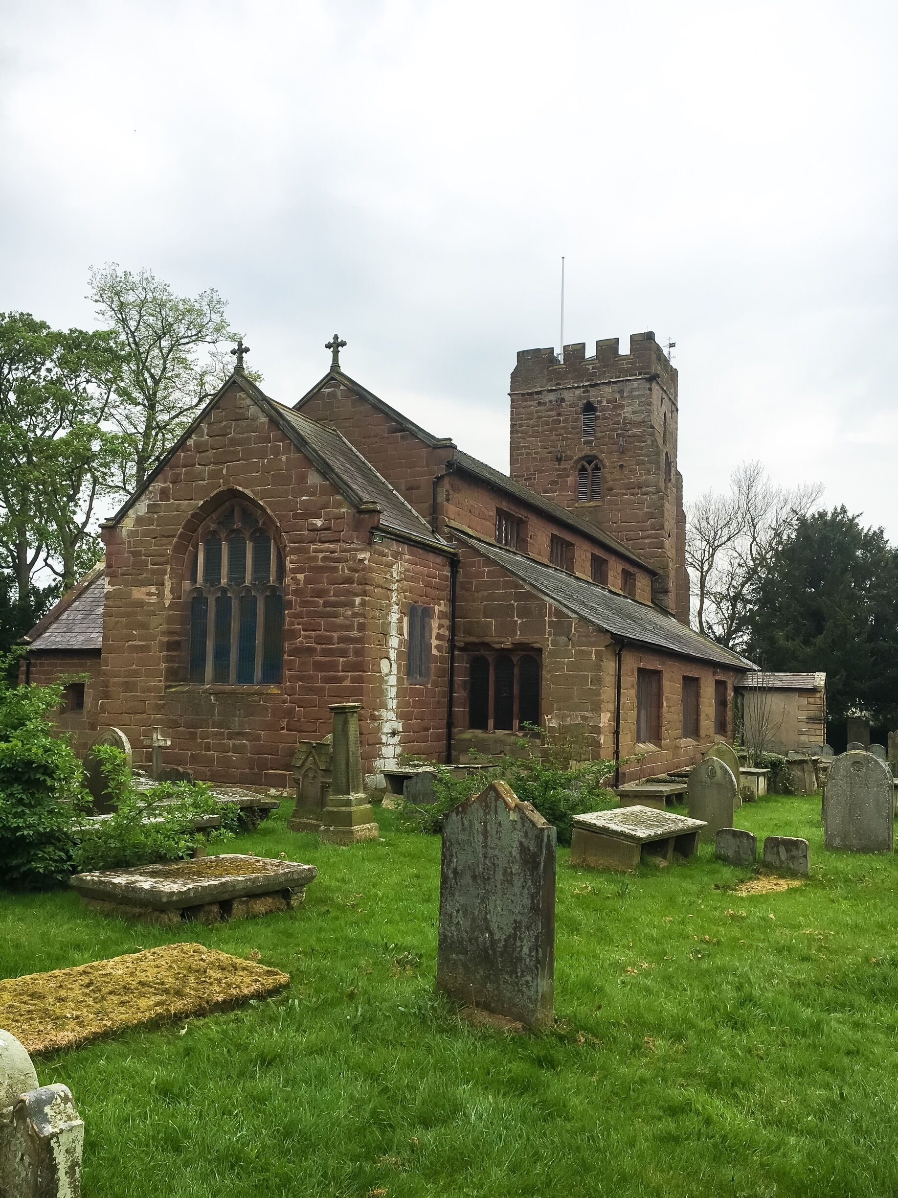 A church with a tall tower and a graveyard in front.