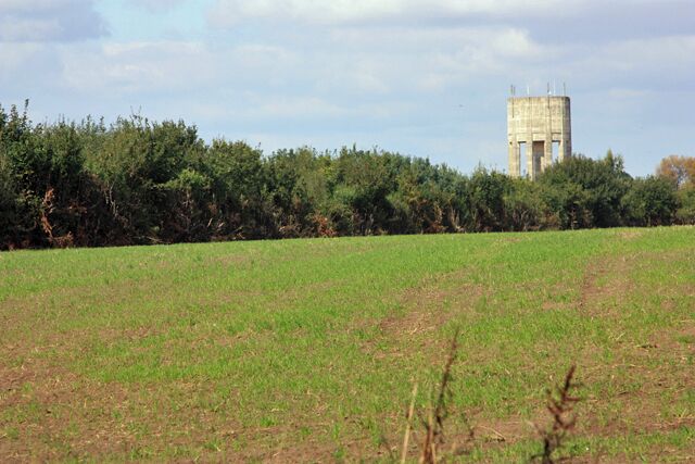 A grassy field with a water tower in the background.