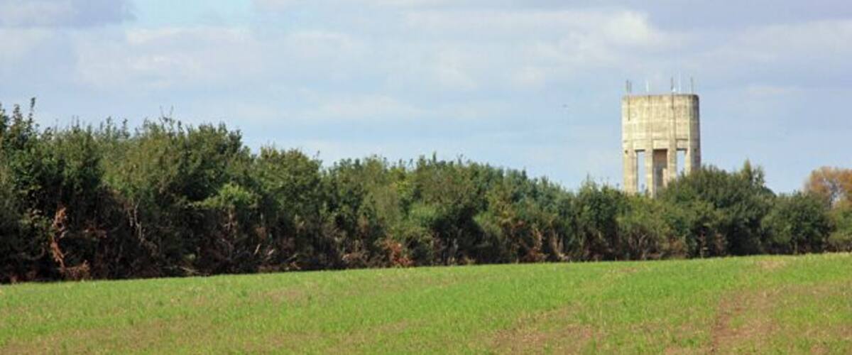 A grassy field with a water tower in the background.