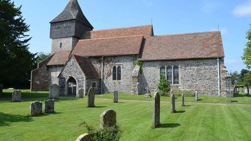 The church dates from the late 11th century onwards and was restored in 1877 by Ewan Christian. It is built with knapped flint and stone dressings with tiled roofs. There is a west tower, nave with north and south aisles, south porch and chancel with north and south chapels. The tower is from the 13th century with an earlier base. In the 14th century a square timber framed belfry with a short spire was built to form the second stage of the tower. it is heavily buttressed. There are six bells. The nave is continuous with the south wall of the tower, and follows the outline of the original Norman nave. Originally there were no side aisles or chapels and the chancel would have been much shorter. The south aisle dates from the 14th century with earlier origins. It has a 15th century crown post roof. Both aisles are from an early date, possibly before 1200. They were probably added as part of the building programme by Saint Gregory's Priory. The arcades were rebuilt in the 14th century in the Perpendicular style with octagonal piers. The north Chapel was built soon after 1300 and the east window is contemporary with this date. The south Chapel, dedicated to St John the Baptist, is probably a similar date. In the 15th century several wills bequeathed money for repairs. The south Chapel is also known as the Honywood Chapel as there is a monument to Sir Thomas Honywood, died 1622. The style closely resembles the work of Nicholas Stone, although unsigned. There is also a monument to Sir William Honywood, died 1669. Sir William was master of the society of silk merchants and died in his 81st year. His second wife Lady Dorothy Honywood whose monument is nearby died within four months of her husband. There are other dedications to the Honywood's in floor ledgers and monuments. The chancel is Early English and was lengthened in the 13th century replacing the Norman one. The chancel arch was rebuilt in the 14th century. The chancel contains a piscina. The font bowl is from the 12th century made of Purbeck marble and supported on modern shafts. The church was restored in 1877, it was in need of urgent attention and was described as being "in a damp and miserable condition". Box pews were removed, choir stalls were placed in the chancel and the altar platform was extended. The roof of the Honywood Chapel was rebuilt, paid for by the Honywood family. Most of the money for the rest of the repairs was from public subscription.