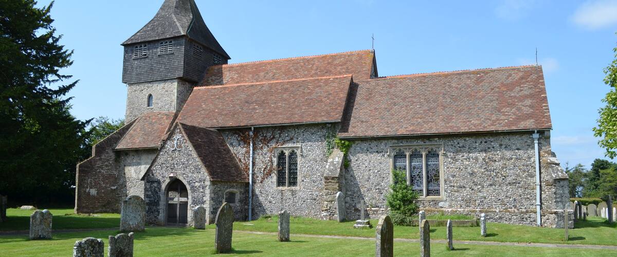 A church with a stone tower and a graveyard.
