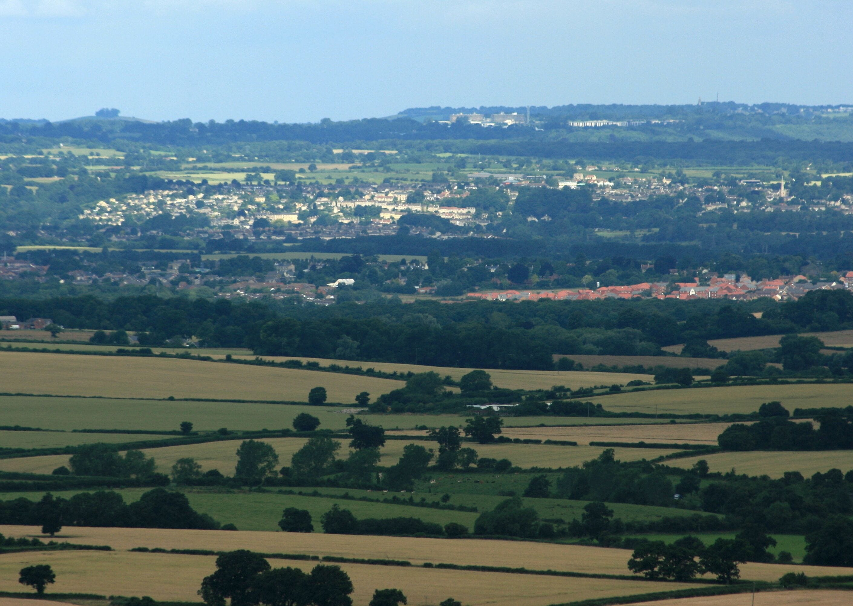 View from Coulston Hill, near Edington From Coulston Hill we look over the rich farmland of west Wiltshire with Trowbridge trying to hide between the hills and not quite succeeding. Further on Bradford on Avon makes a far better show with Christchurch standing bold near the right hand edge of the frame nearly nine miles away. However, at twice the distance, Bradford is easily outdone by Beckford's Tower on Lansdown. ST7367 There it is, on the skyline, at 18 miles, a little to the left of Christchurch. Even this is not the end, look to the left of the picture, on the skyline again and there is Kelston Round Hill. ST7167 That is at a distance of 21 miles. If you live in the area (or even if you do not) and can positively identify any other landmark I would like to hear from you. Your own house may be there.
