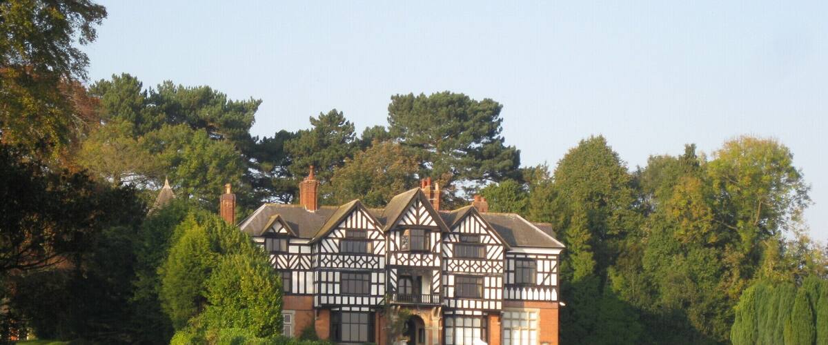 A Tudor-style house with a large garden and a pond.