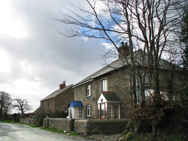 A stone house with a blue roof and a small attached structure.