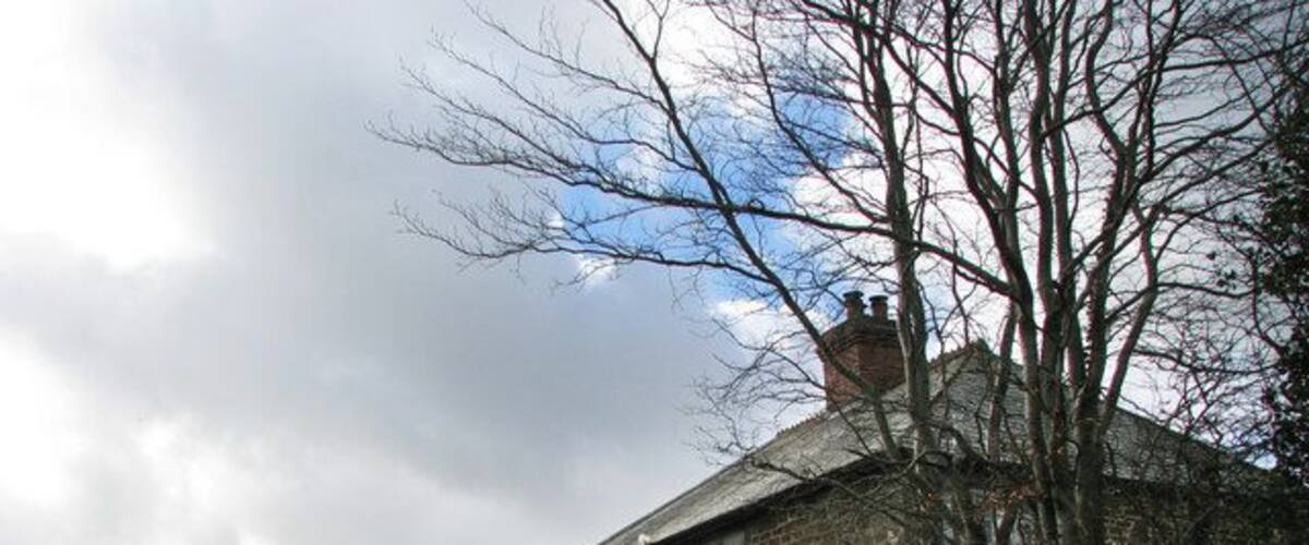 A stone house with a blue roof and a small attached structure.