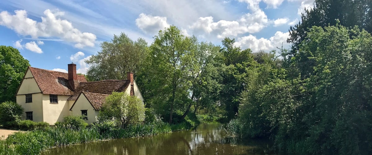 A river with a house on the left bank and dense greenery on the right.