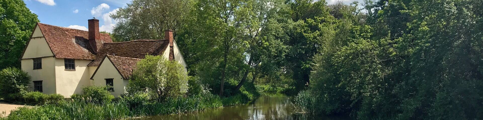 A river with a house on the left bank and dense greenery on the right.