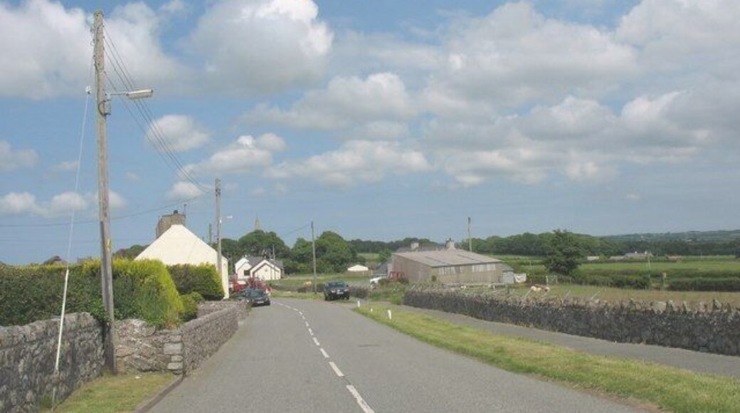 The B 4421 at the southern entrance to Llangaffo village The village school and the steeple of St Caffo's Church can be seen in the centre of the photograph.
