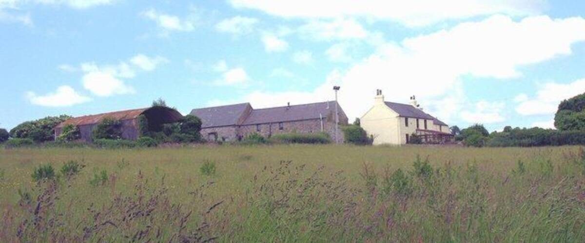 A rural landscape with a field, a farmhouse, and a barn.