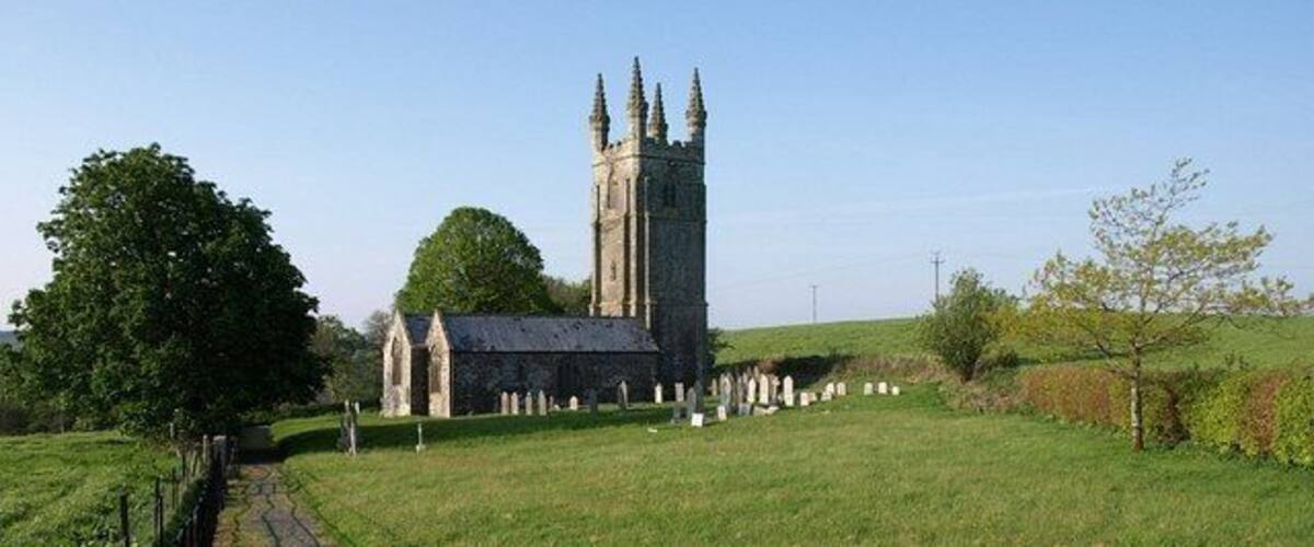 A church with a tall tower and a graveyard in the foreground.