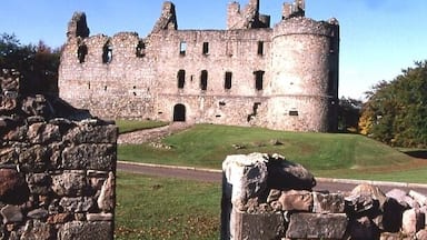 A historic stone castle with multiple towers and a grassy courtyard.