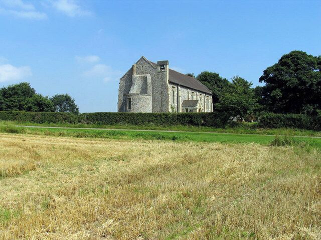 A stone building in a field with a clear sky.