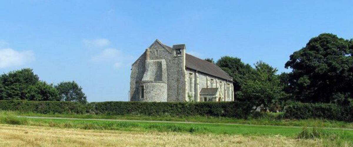 A stone building in a field with a clear sky.