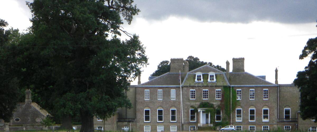 A large brick building with multiple windows and a prominent tree in the foreground.