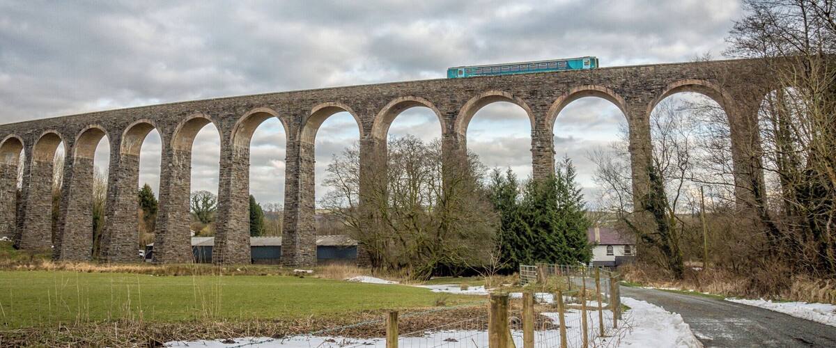 A stone viaduct with a train crossing over it.