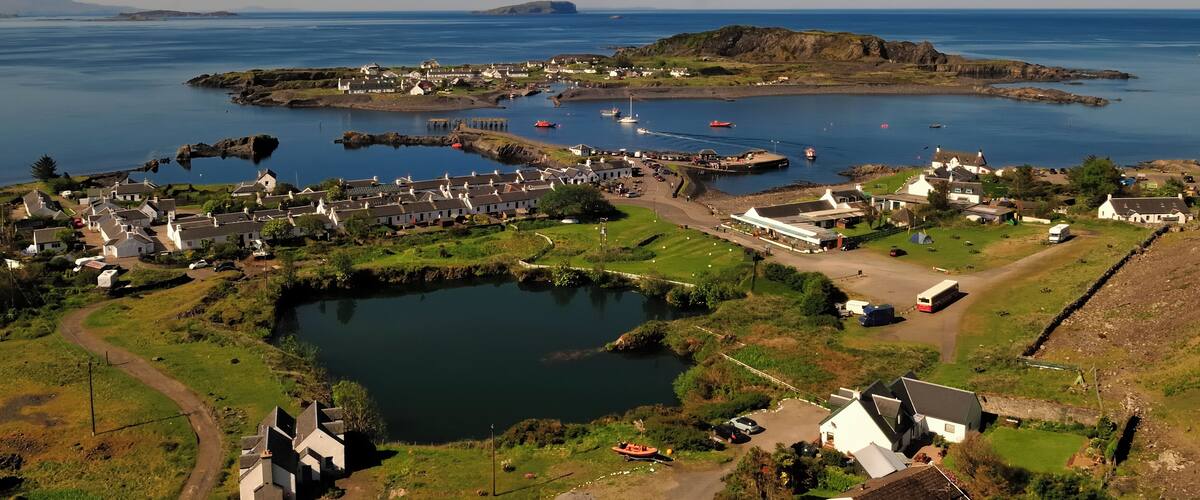 A coastal village with a harbor, boats, and a small island in the background.