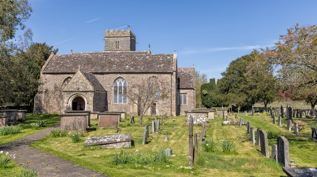A historic church with a stone facade, a bell tower, and a cemetery with headstones.