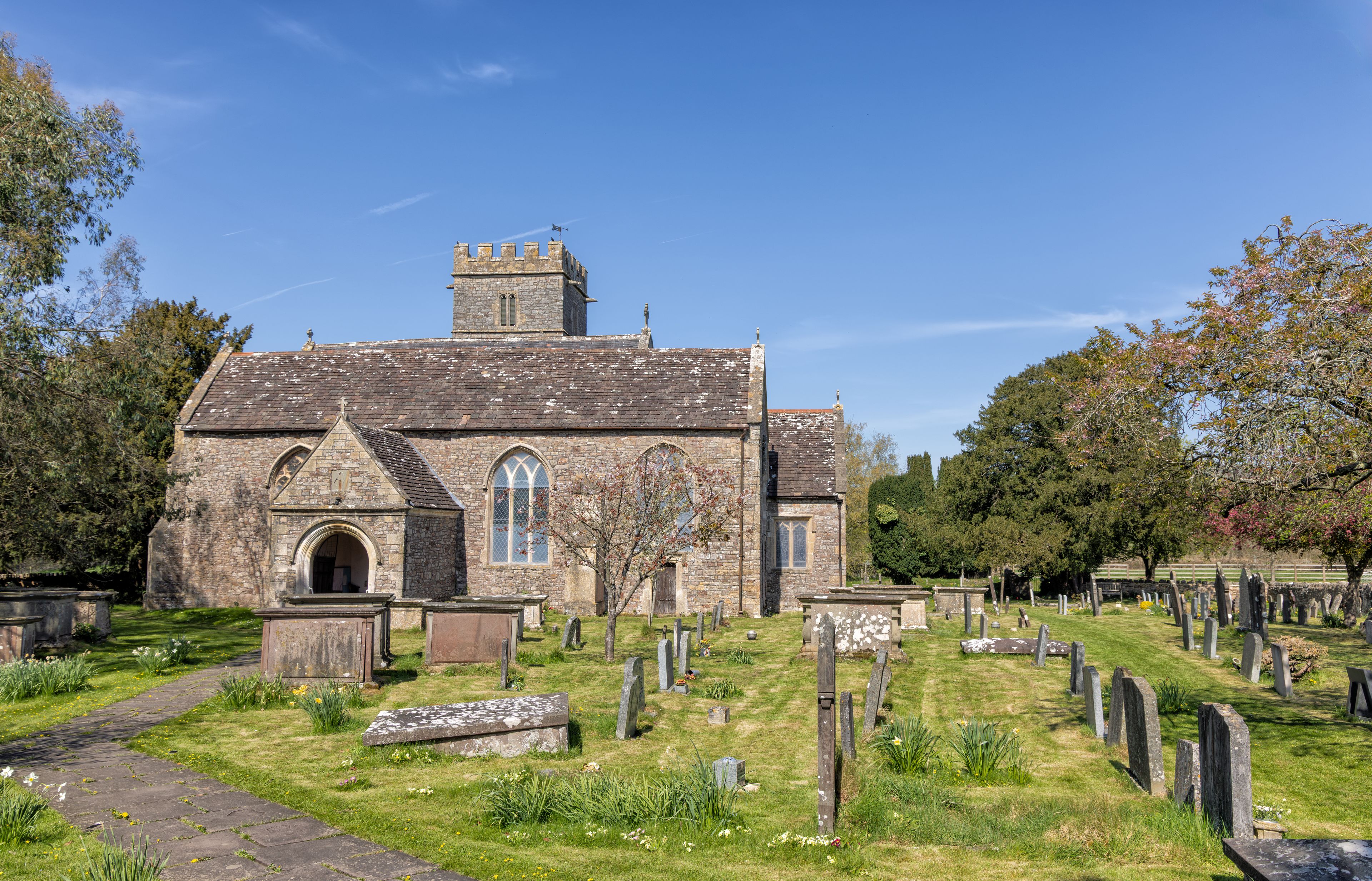 A historic church with a stone facade, a bell tower, and a cemetery with headstones.