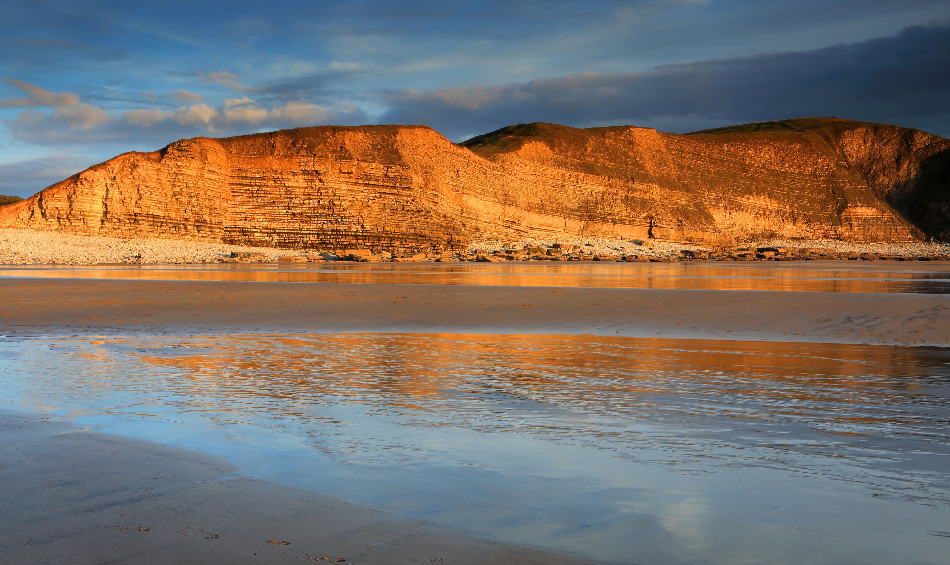Un paisaje costero con acantilados escalonados y una playa tranquila.