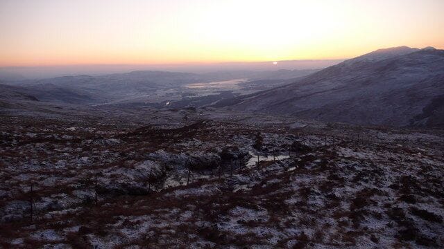 Moorland slopes of Cairn Eididh towards Loch Carron The wire fencing in foreground divides the Coulags grazings and the deer forest of the Achnashellach estate. The fencing was put up in the early 1900s and has long since fallen into disrepair. Loch Carron a glacial trough. The mountains of Skye in distance.
