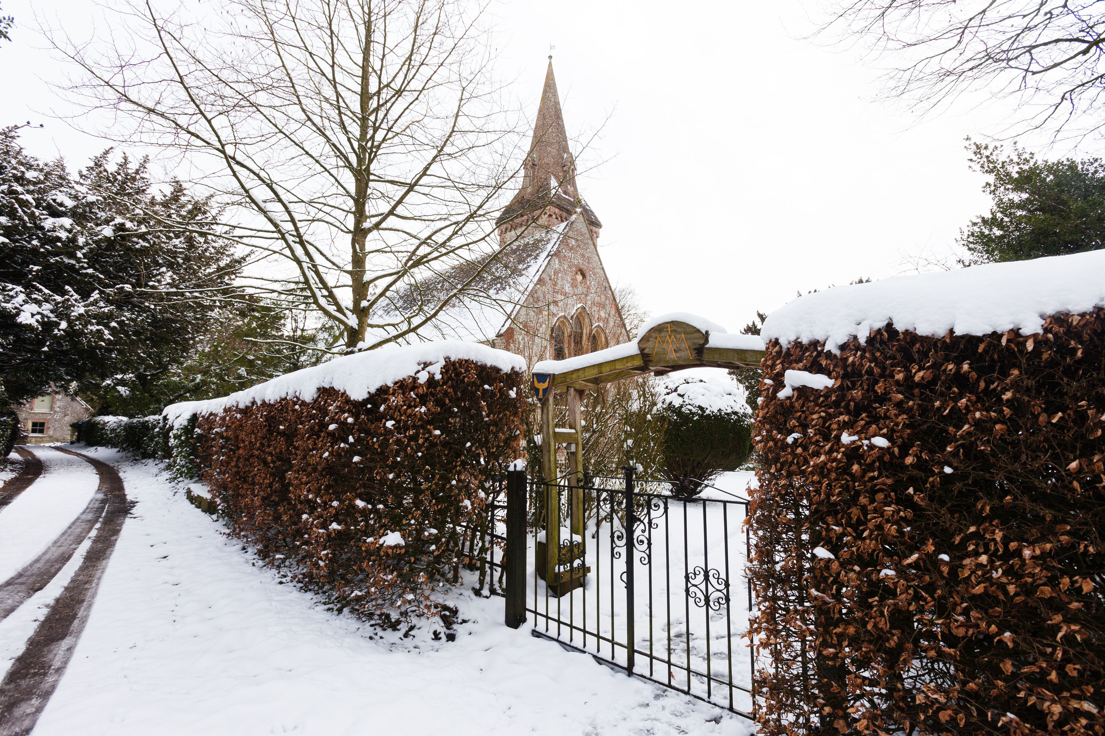 A snow-covered pathway leading to a church with a spire.