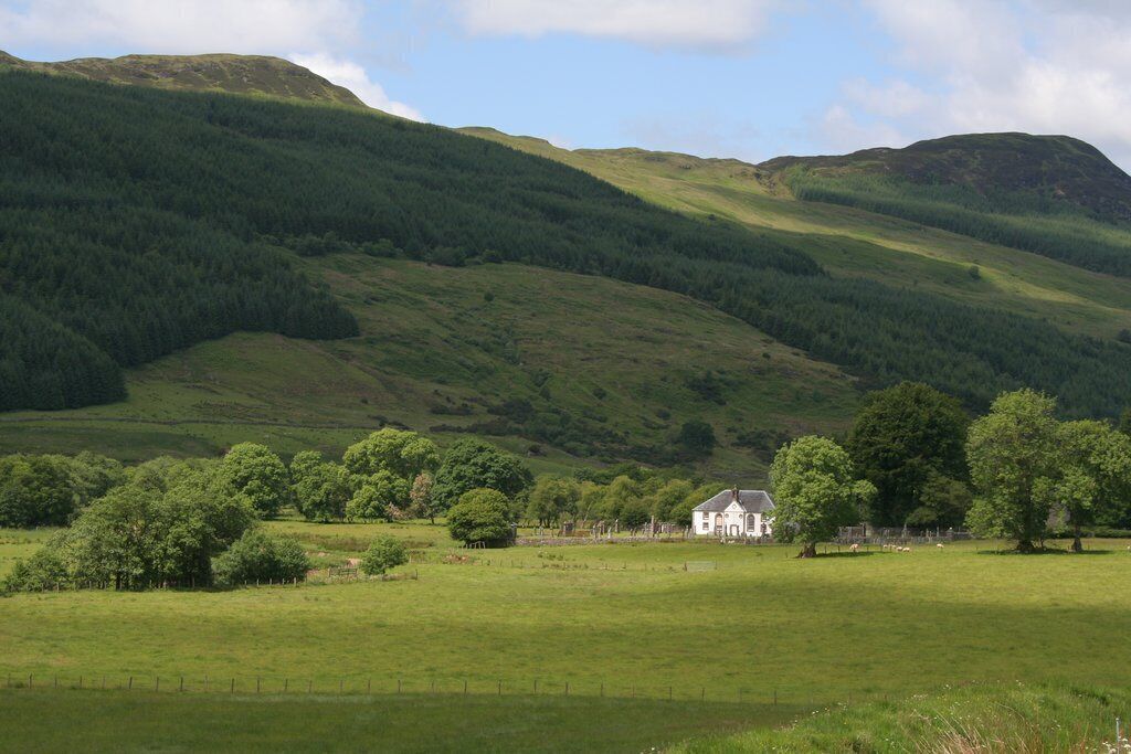 A white house surrounded by lush green fields and rolling hills.