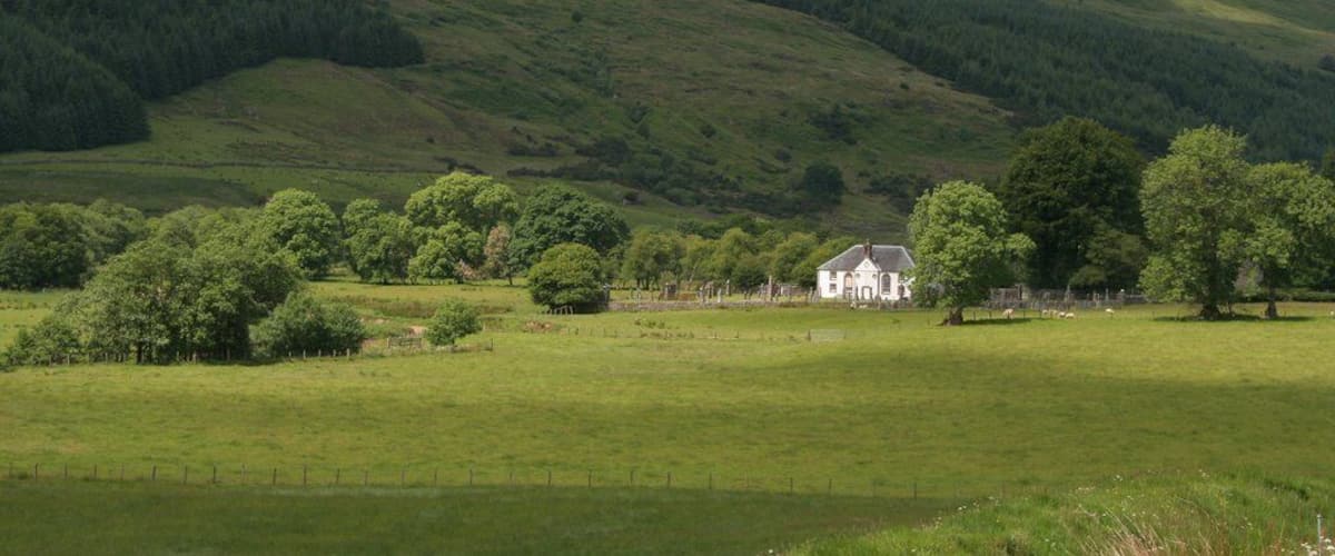 A white house surrounded by lush green fields and rolling hills.
