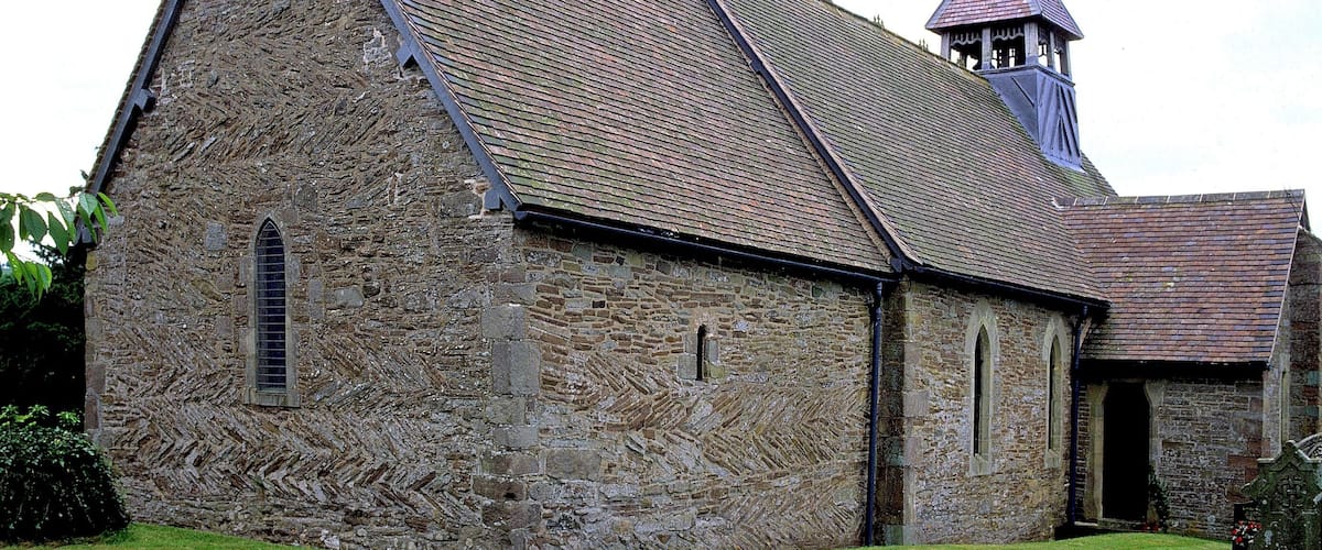 A stone church with a bell tower and a grassy courtyard.