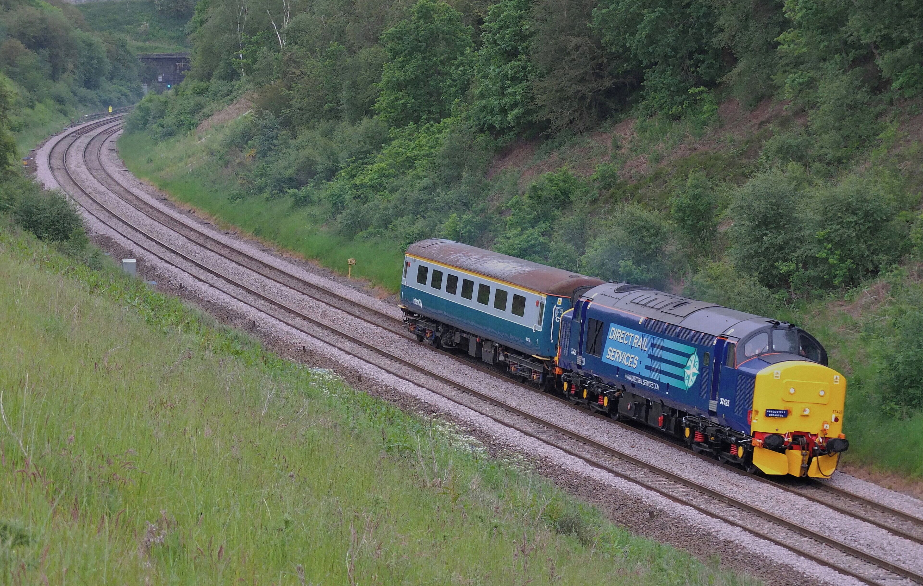 A train on a curved railway track surrounded by lush greenery.