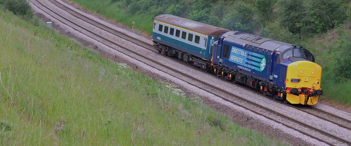 A train on a curved railway track surrounded by lush greenery.