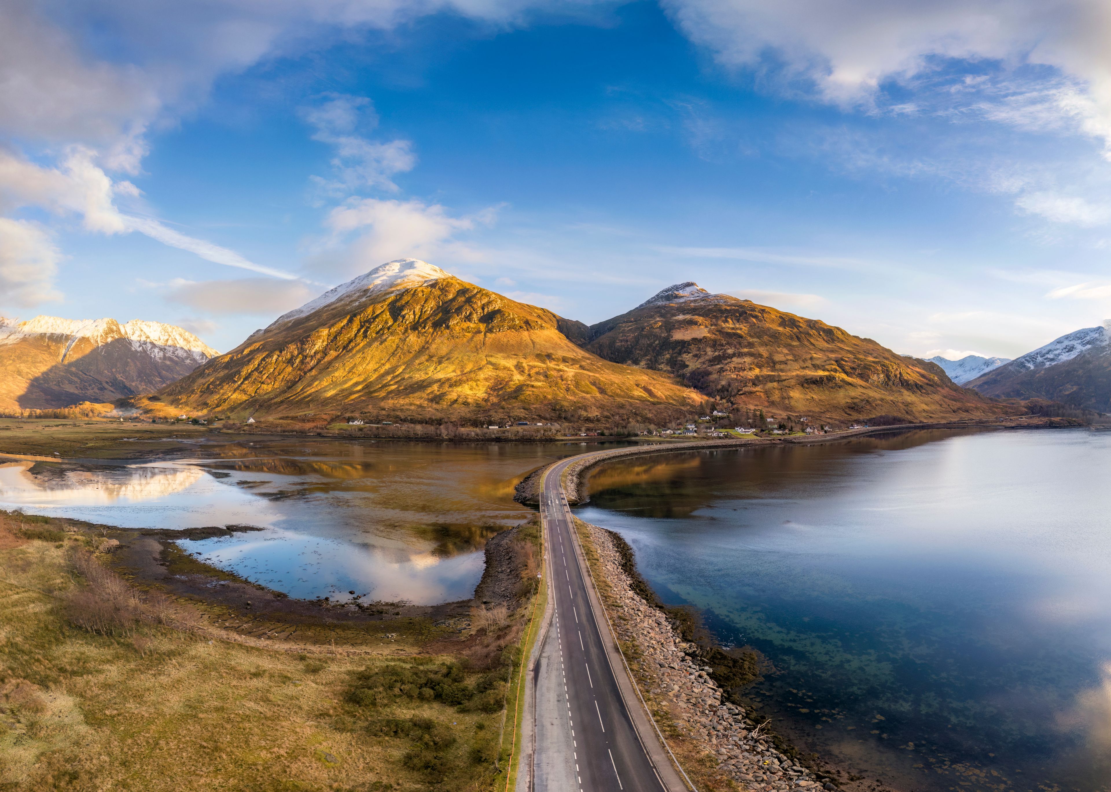 A mountain range with a lake and a road.