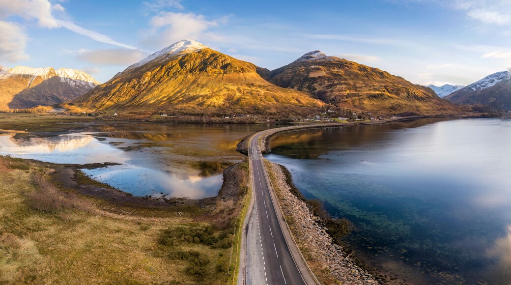 A mountain range with a lake and a road.