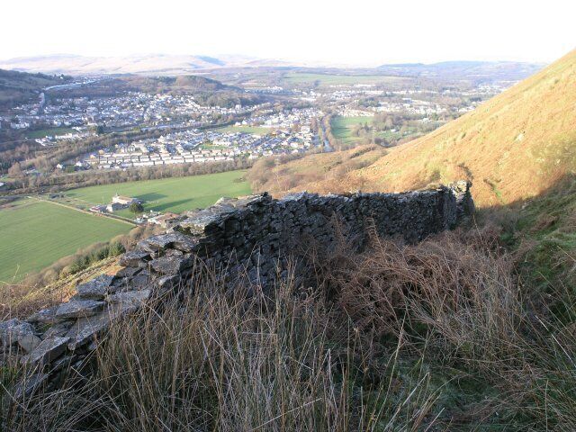 Dry stone wall above Ystalyfera This dry stone wall is on a little used section of St Illtyd's Walk above Ystalyfera. Rather than protecting the footpath, over the years a buildup of stones combined with retention of water has made the footpath very difficult to walk on.