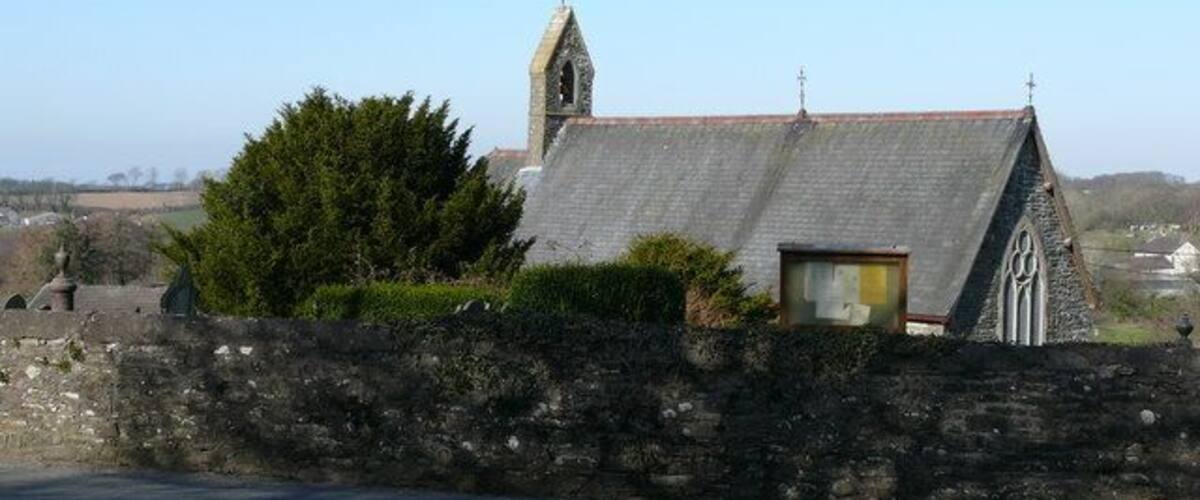 A stone church with a bell tower and a small window.
