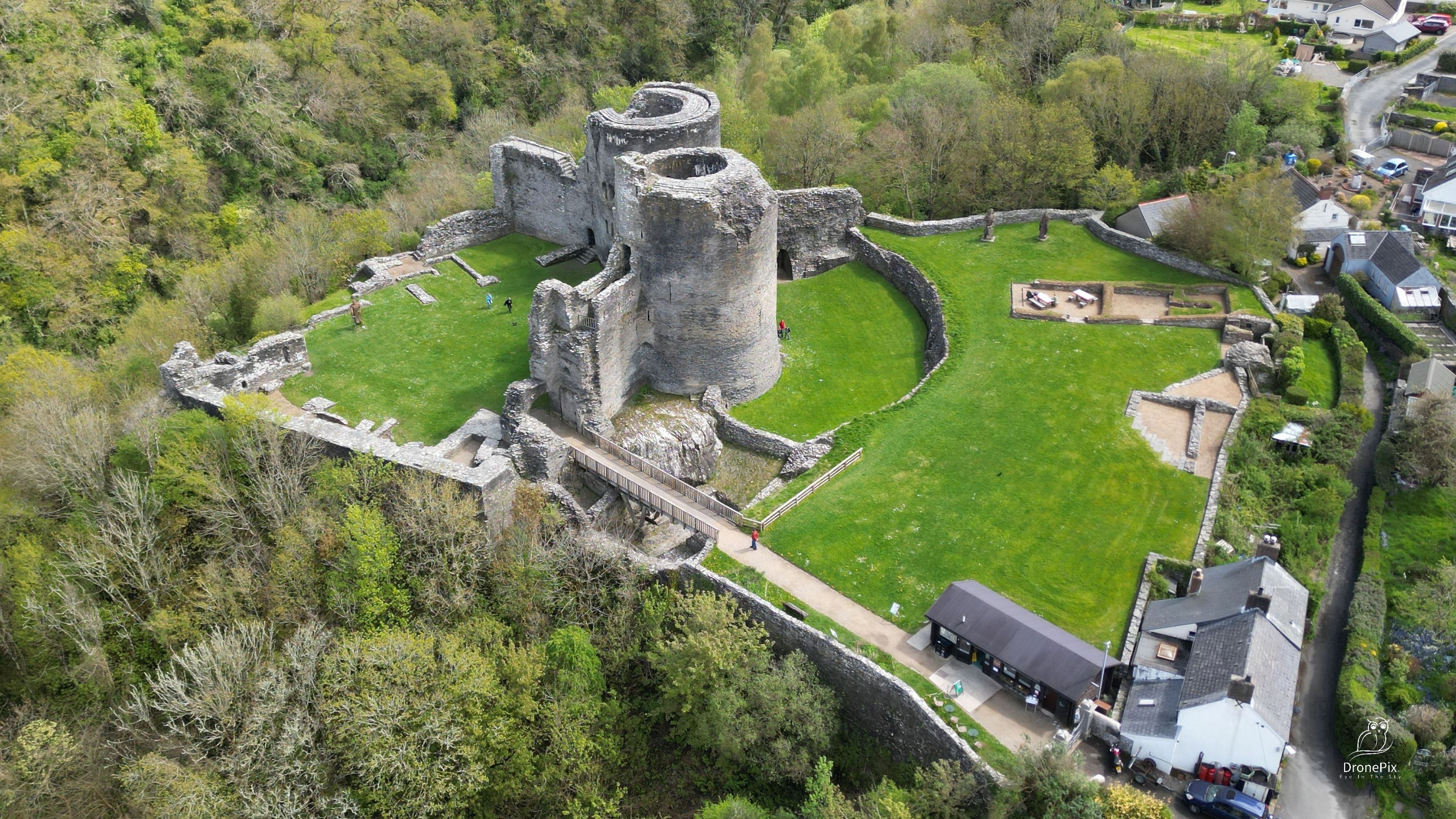 An aerial view of a historic castle surrounded by lush greenery and modern buildings.
