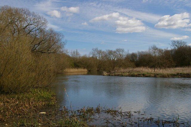 A calm river with trees and grassy banks.