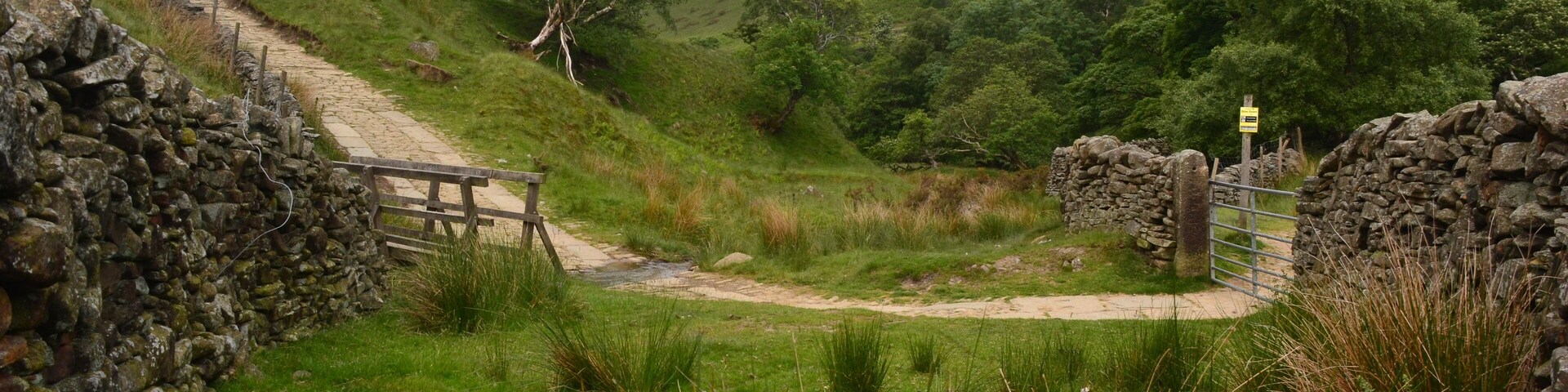A stone wall, a wooden gate, and a grassy path leading uphill.